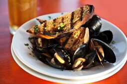 Mussels in a beer broth with garlic and herbs served with grilled bread