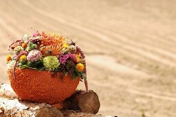 Autumnal flower arrangement in polystyrene bowl covered in lentils