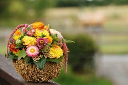 Autumnal flower arrangement in polystyrene bowl covered in lentils