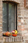 Autumnal flower arrangement in hollowed-out pumpkins on windowsill