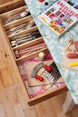 Rustic kitchen table covered in oilcloth with open cutlery drawer