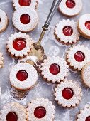 Jammy shortbread biscuits dusted with icing sugar on baking paper