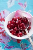 Pomegranate seeds, rose petals and a silver spoon