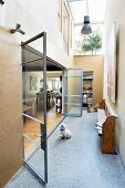 High-ceilinged hallway with skylight and open glass folding door with view into living area