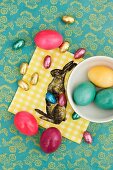Easter eggs and chocolate eggs on a napkin decorated with an Easter bunny