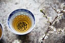 Green tea in an oriental tea bowl next to a sprig of cherry blossom