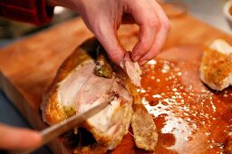 A roast chicken being carved, meat being removed from the bone