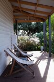 Holzliegestühle auf überdachter Terrasse eines Holzhauses