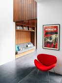 Framed vintage poster above retro armchair in front of custom shelving with integrated reading niche