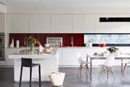 Long fitted kitchen counter, island counter and dining area with Eames chairs in open-plan