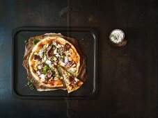 Lamb pizza with feta cheese and mint yoghurt on a dark brown surface
