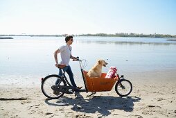 Mann mit Hund und Fahrrad auf dem Weg zum Strandpicknick