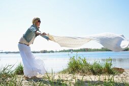Woman spreading picnic blanket on beach