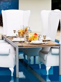 Festively set table and throne-like, white, upholstered armchairs on special floor insert in swimming pool