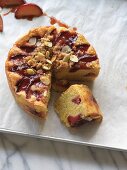 Sliced, gluten free plum cake with almonds and crumbles on a baking tray