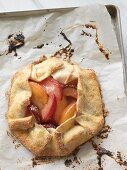 A peach and plum tart on a baking tray lined with paper