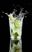 Caipirinha-Splash vor schwarzem Hintergrund