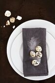 A place setting with a grey napkin decorated with quails eggs