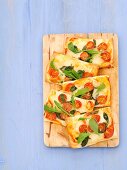 Slices of mozzarella, cherry tomato and basil pizza