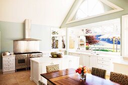 Giebelverglasung und Faltglasfenster in weiträumiger Küche mit Unterschrankblock und doppeltem Edelstahlherd
