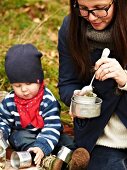 A woman and a child eating beetroot soup at an autumnal picnic