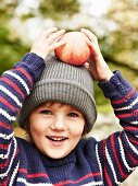 Mädchen hält Apfel auf dem Kopf beim Herbstpicknick