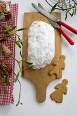 A stollen dusted with icing sugar on a wooden board