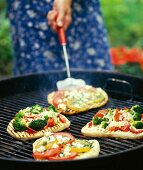 Pita bread pizzas being cooked on a barbecue