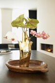Gold, designer vase of orchids and anthuriums on dining table