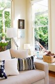 Corner of sunny room with two windows and pale, timeless sofa