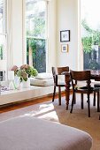 Antique table in corner of sunny dining area with multiple windows and low, broad windowsill