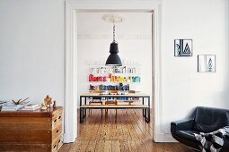 Vintage atmosphere with repurposed vaulting box and black leather armchair; DIY dining set below industrial lamp and stucco ceiling seen through open doorway