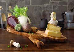 Vegetables and cheese being compared on a chopping board