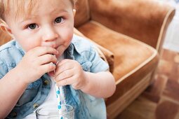 Kleiner Junge trinkt Milch mit Strohhalm