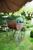 A sales exhibitions under a pergola in the garden of a French country house - plant pots with price labels in a an antique pram