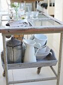 Various kitchen utensils and crockery on serving trolley in kitchen