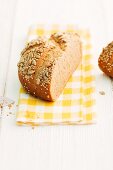 Half a loaf of sunflower seed bread on a checked napkin