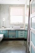 Washstand with frosted glass doors below window in minimalist bathroom