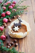 A Christmas biscuit on a mini sponge cake on a wooden surface