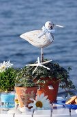 Various potted plants and bird figurine on table against ocean backdrop