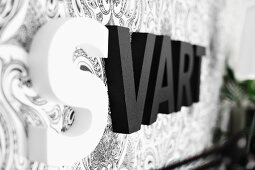 Black and white ornamental letters on wallpapered wall