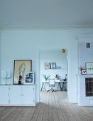 White sideboard next to open door with view of office area; continuous wooden board floor