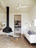 Suspended, cast iron fireplace, classic coffee table and white sofa in simple living room