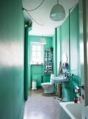 View through open door into narrow bathroom in period apartment painted mint green with white pendant lamps