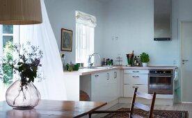 Moderne Landhaus-Küchenzeile Übereck, im Vordergrund Glasvase auf Holztisch