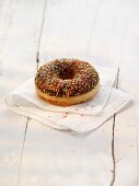 A doughnut with chocolate glaze and colourful sugar sprinkles