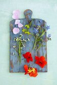Various edible flowers on a wooden board (seen from above)