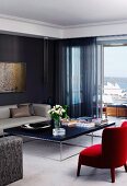 Red armchair, custom-made delicate coffee table and dark translucent curtains on balcony door in elegant living room