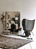 Textiles with graphic patterns, mesh easy chair, painted wooden stool in front of life-sized black and white photo of African family