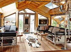 Lounge area with leather sofa set and animal-skin rug in roof space of modern chalet
